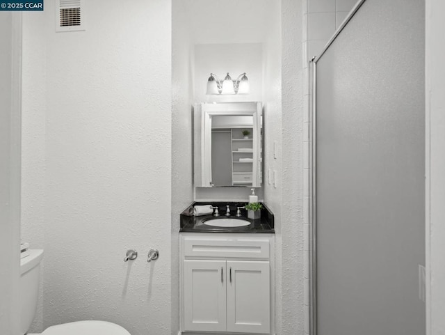 bathroom featuring vanity, toilet, and walk in shower