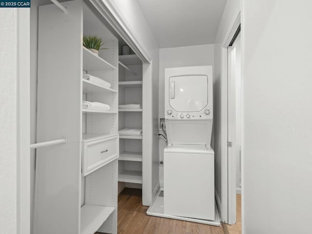 laundry room featuring stacked washer / drying machine and light hardwood / wood-style floors