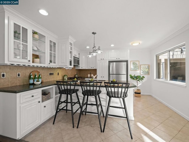 kitchen with backsplash, stainless steel appliances, ornamental molding, white cabinets, and decorative light fixtures