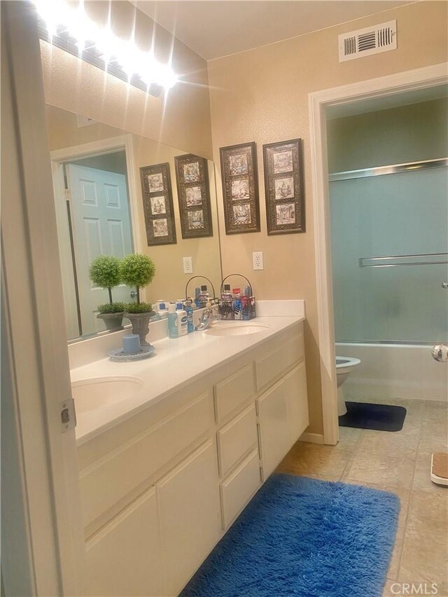 full bathroom with vanity, tile patterned floors, toilet, and combined bath / shower with glass door