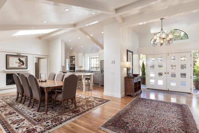 dining area featuring beamed ceiling, an inviting chandelier, high vaulted ceiling, and light hardwood / wood-style floors