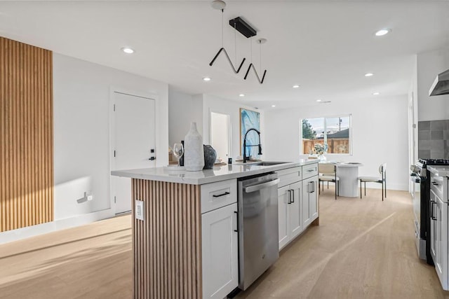 kitchen featuring sink, stainless steel appliances, an island with sink, white cabinets, and decorative light fixtures