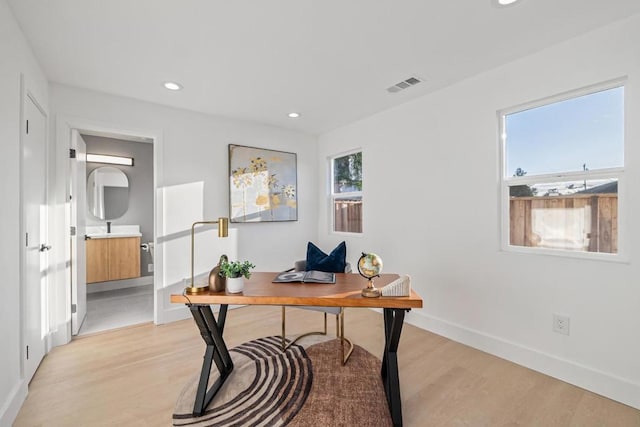 office with light hardwood / wood-style flooring and a wealth of natural light