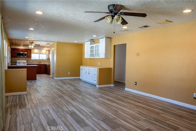 kitchen with wood finished floors, visible vents, open floor plan, range, and stainless steel microwave