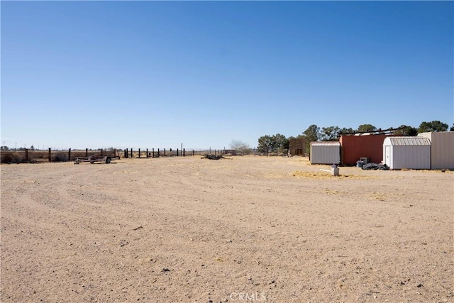 view of yard with a storage shed, a rural view, and an outbuilding