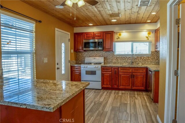 kitchen featuring tasteful backsplash, sink, light stone counters, and white gas range oven