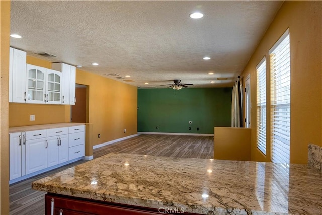 kitchen with dark wood-style flooring, glass insert cabinets, visible vents, and white cabinetry