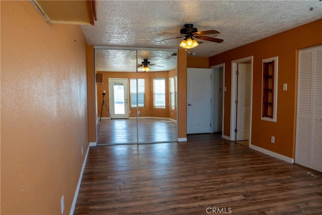 interior space with ceiling fan, a textured ceiling, baseboards, and wood finished floors