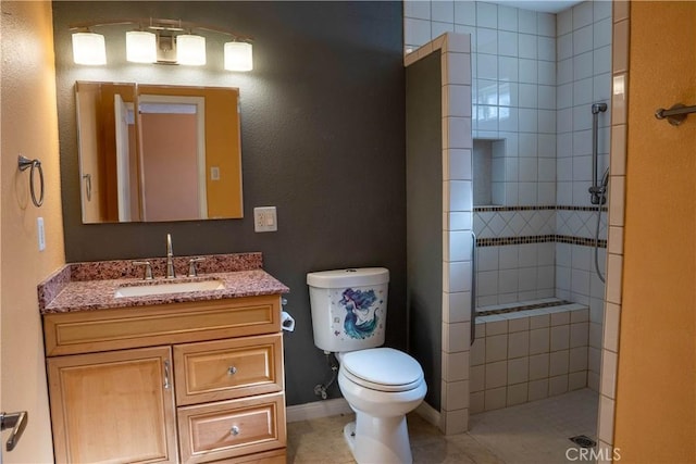 full bathroom featuring toilet, vanity, tile patterned flooring, tiled shower, and baseboards