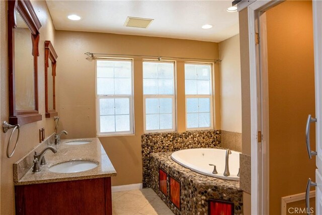 bathroom featuring a garden tub, baseboards, visible vents, and a sink