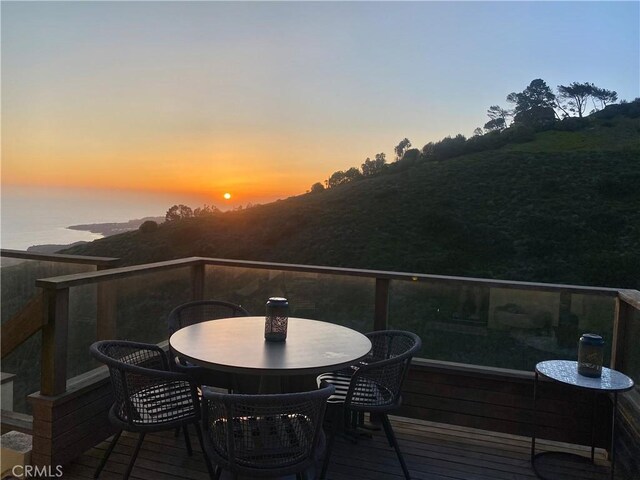 deck at dusk featuring a water view