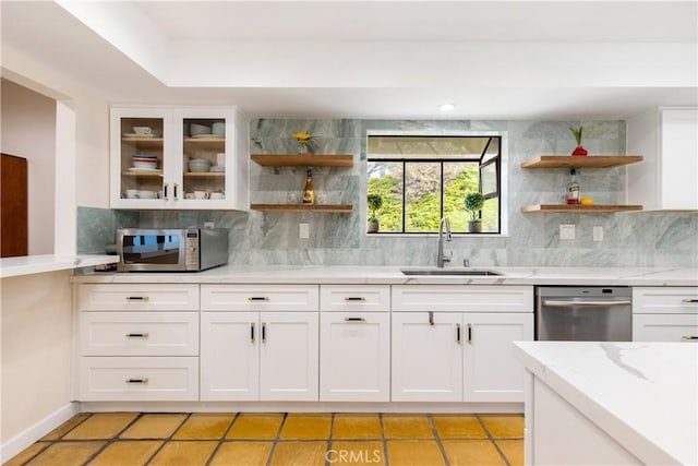 kitchen with appliances with stainless steel finishes, sink, white cabinetry, light stone countertops, and decorative backsplash