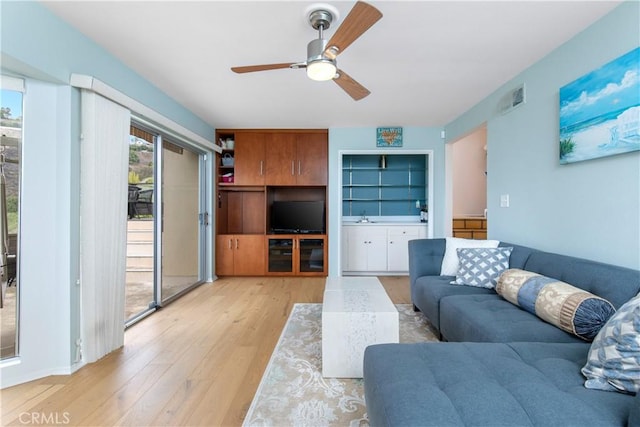 living room with light wood-type flooring, sink, and ceiling fan