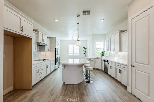 kitchen with white cabinetry, stainless steel dishwasher, a center island, and hanging light fixtures