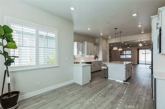 kitchen with pendant lighting, a kitchen island, white cabinets, a kitchen bar, and decorative backsplash