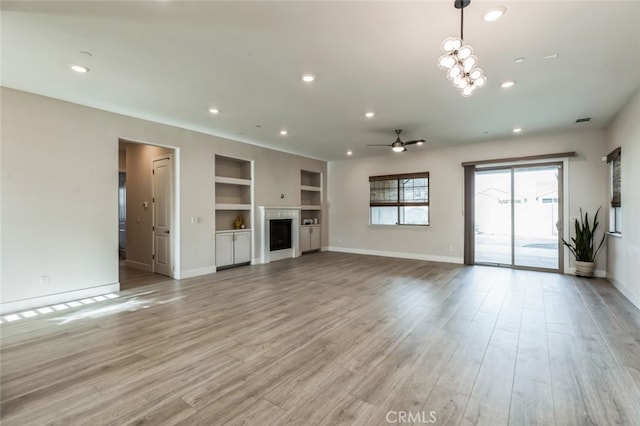 unfurnished living room with light hardwood / wood-style flooring, ceiling fan, and built in shelves