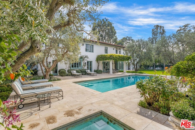 view of pool with a hot tub and a patio area