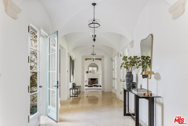 hallway featuring lofted ceiling and an inviting chandelier