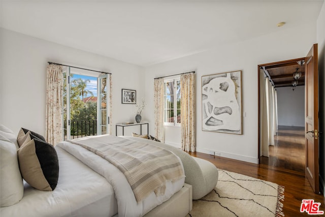 bedroom featuring multiple windows, dark wood-type flooring, and access to exterior