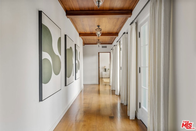 hallway featuring beamed ceiling, a barn door, wooden ceiling, and light wood-type flooring