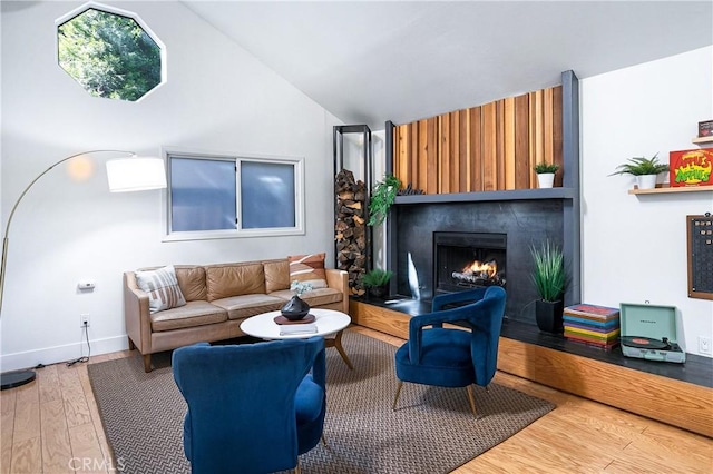 living room with lofted ceiling, wood-type flooring, and a large fireplace