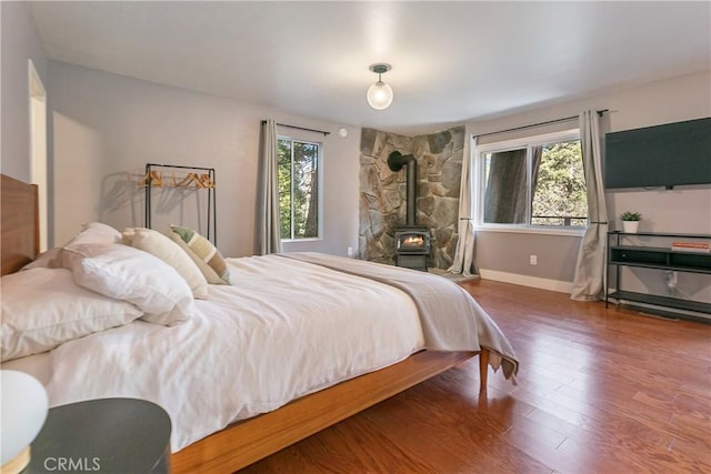 bedroom with hardwood / wood-style flooring and a wood stove