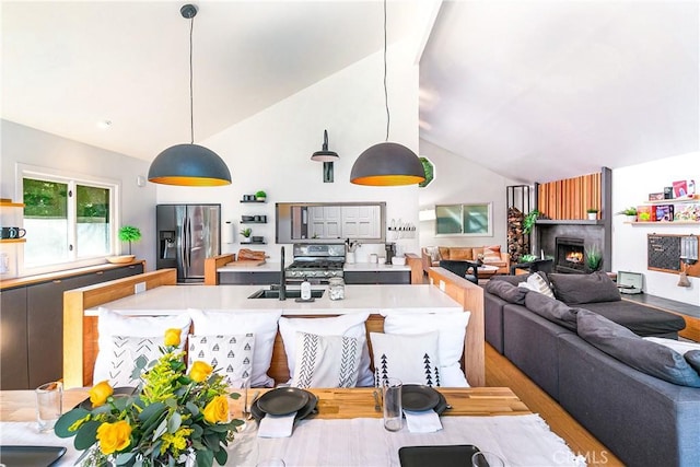 kitchen with high vaulted ceiling, decorative light fixtures, sink, stainless steel appliances, and light hardwood / wood-style flooring