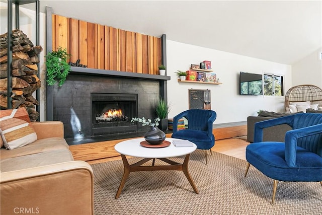 living area featuring a large fireplace, vaulted ceiling, and hardwood / wood-style floors