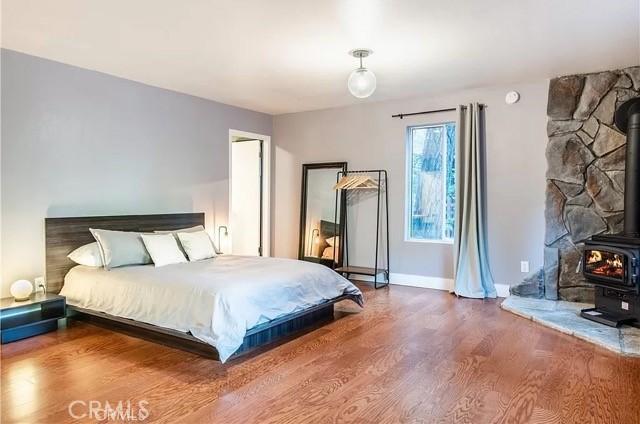 555 Dover Ct, Lake Arrowhead, CA 92352 - bedroom featuring baseboards, wood finished floors, and a wood stove