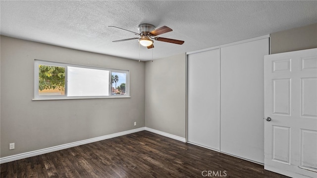 unfurnished bedroom featuring dark wood-type flooring, a textured ceiling, ceiling fan, and a closet