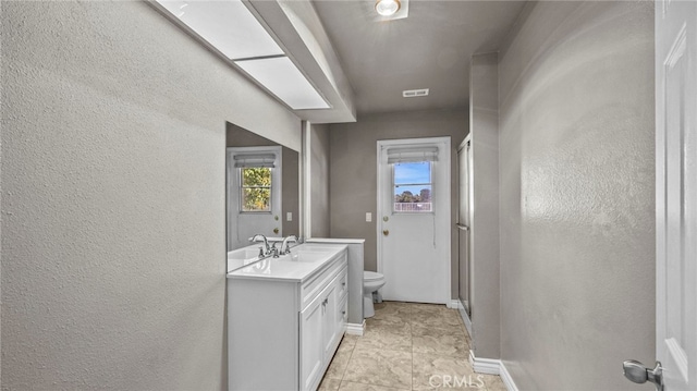 bathroom featuring vanity, toilet, and a shower with door