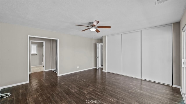 unfurnished bedroom featuring dark hardwood / wood-style flooring, a textured ceiling, ceiling fan, and a closet