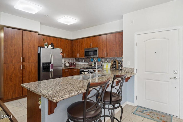 kitchen featuring light tile patterned floors, a breakfast bar area, appliances with stainless steel finishes, backsplash, and kitchen peninsula