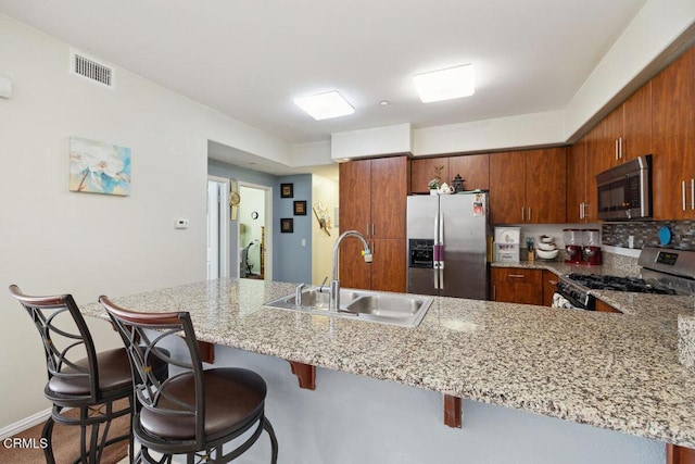 kitchen featuring sink, appliances with stainless steel finishes, tasteful backsplash, a kitchen bar, and kitchen peninsula