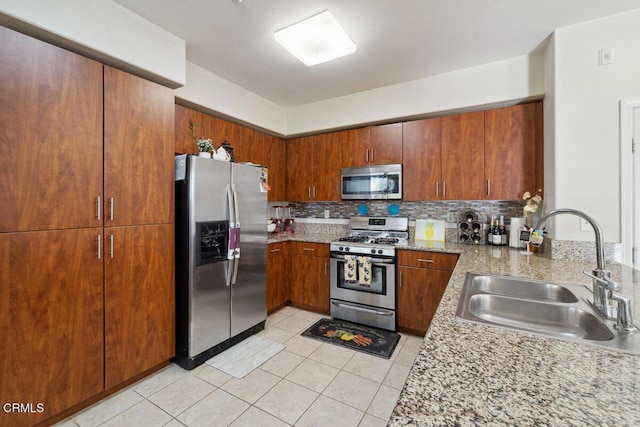 kitchen with sink, light stone counters, light tile patterned floors, appliances with stainless steel finishes, and backsplash