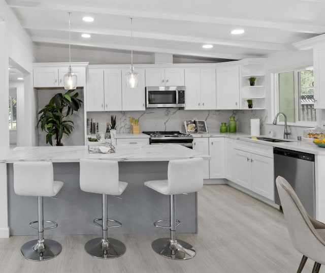 kitchen featuring stainless steel appliances, sink, hanging light fixtures, and white cabinets