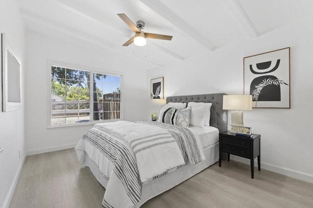 bedroom featuring ceiling fan, wood-type flooring, and beam ceiling