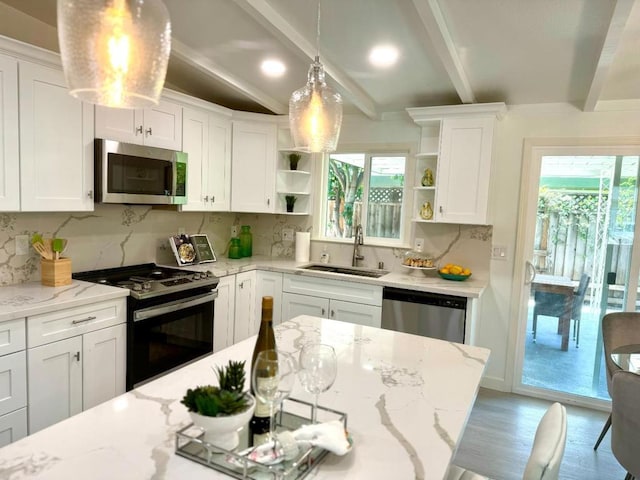 kitchen with sink, white cabinetry, light stone counters, hanging light fixtures, and appliances with stainless steel finishes