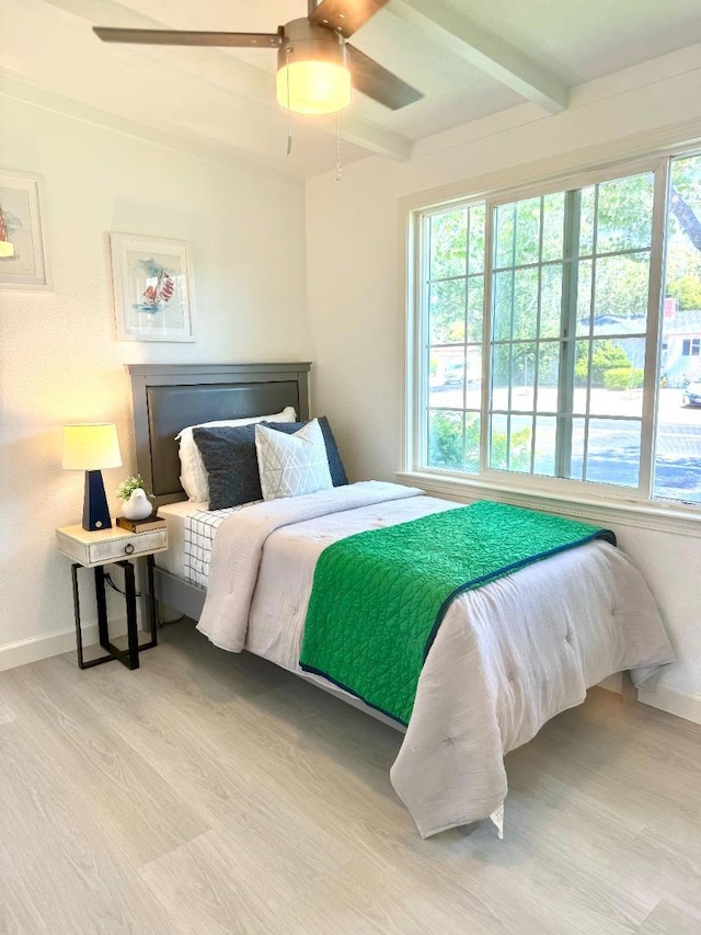 bedroom featuring multiple windows, beam ceiling, light hardwood / wood-style floors, and ceiling fan