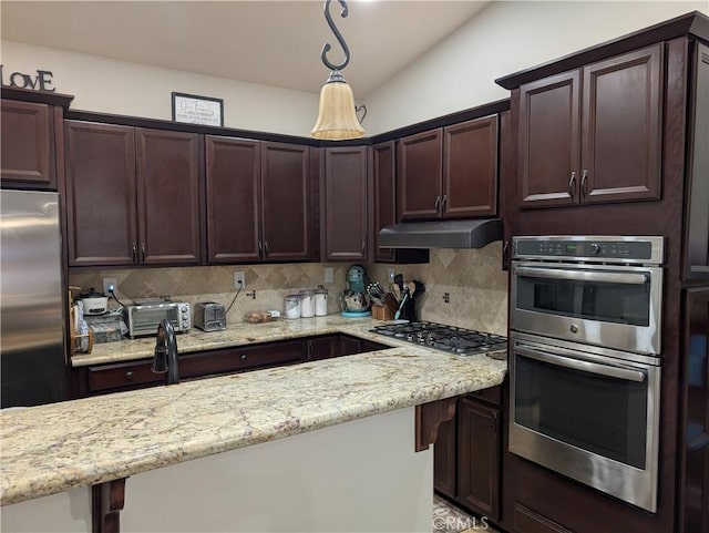 kitchen with vaulted ceiling, hanging light fixtures, appliances with stainless steel finishes, light stone countertops, and decorative backsplash