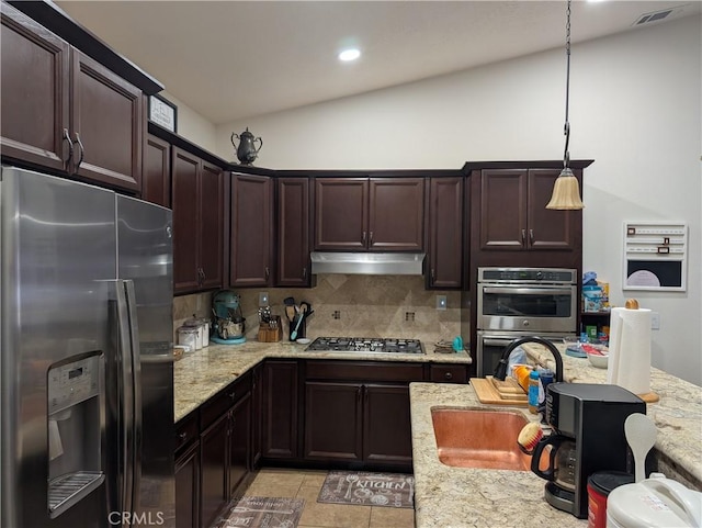 kitchen with appliances with stainless steel finishes, pendant lighting, tasteful backsplash, sink, and light stone counters