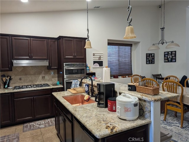 kitchen with pendant lighting, a breakfast bar, appliances with stainless steel finishes, backsplash, and a kitchen island