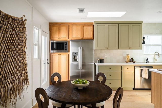 kitchen featuring stainless steel appliances, plenty of natural light, backsplash, and green cabinetry