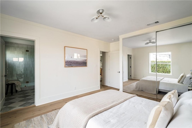 bedroom with ensuite bathroom, crown molding, light hardwood / wood-style floors, and a closet