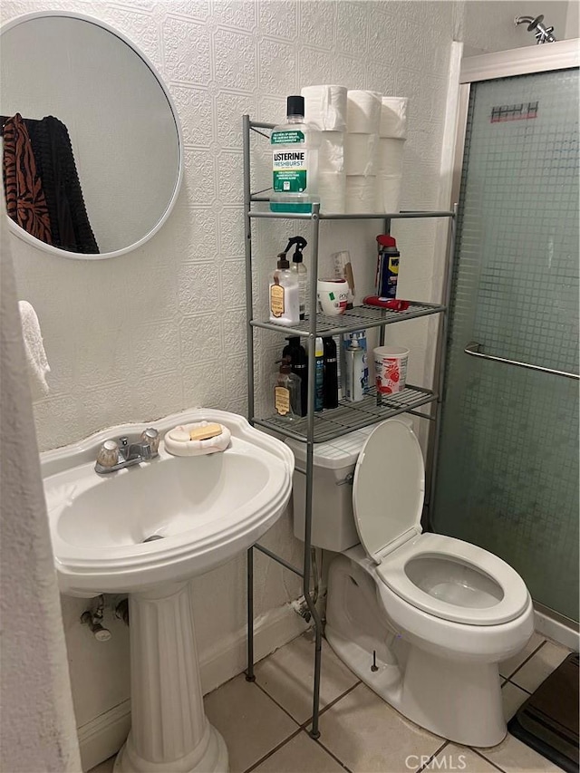 bathroom with tile patterned flooring, a shower with door, and toilet