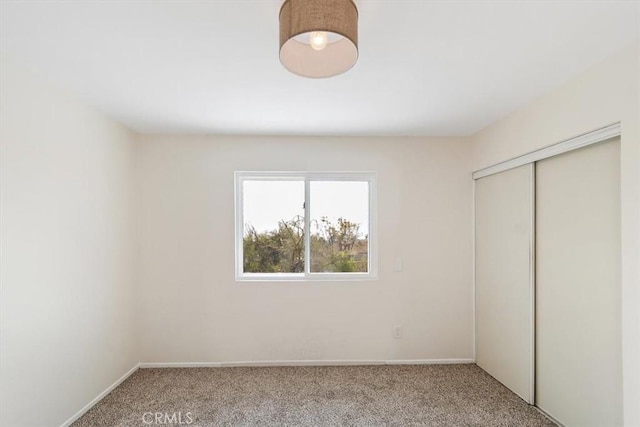 unfurnished bedroom with light colored carpet and a closet