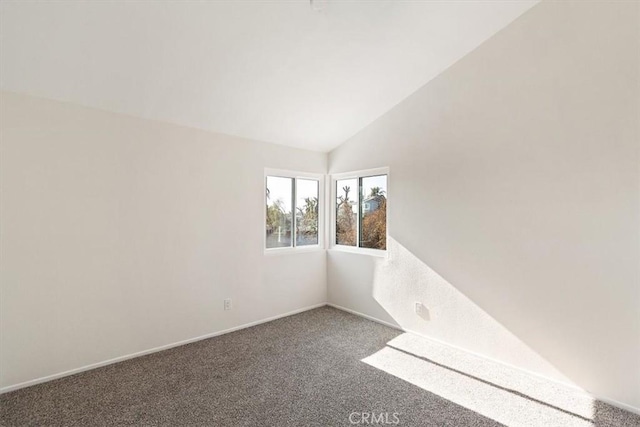 empty room with vaulted ceiling and dark carpet