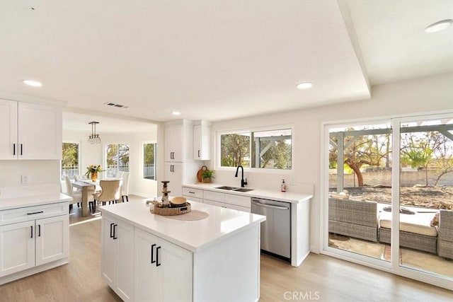 kitchen featuring decorative light fixtures, dishwasher, sink, white cabinets, and light hardwood / wood-style floors