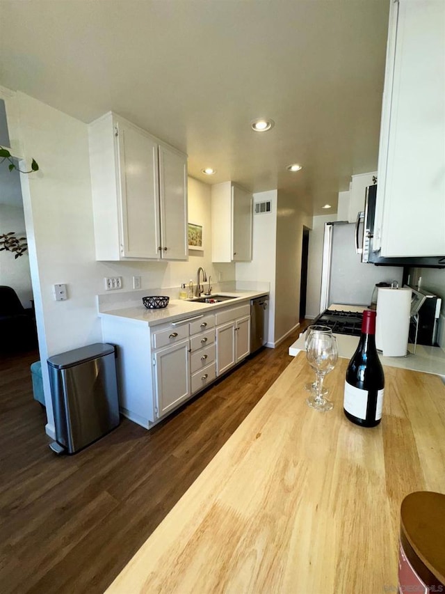 kitchen featuring white cabinetry, stainless steel appliances, dark wood-type flooring, and sink