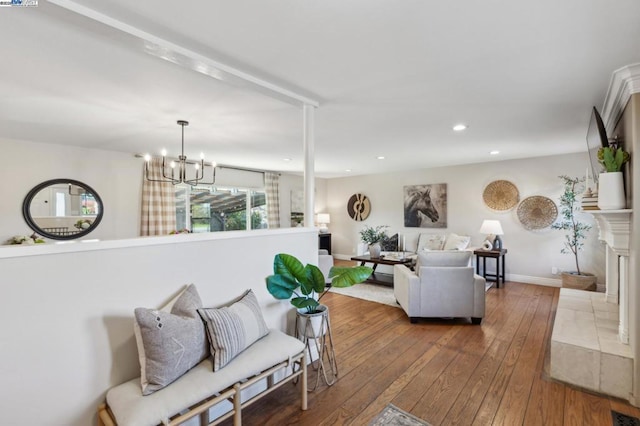 living room with a tiled fireplace, hardwood / wood-style floors, and a notable chandelier